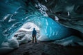 A tourist is standing in an icy, crystal clear cave