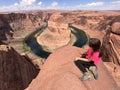 Tourist standing on the ridge and admiring Horseshoe Bend on the Colorado River near Page Arizona on a sunny day Royalty Free Stock Photo