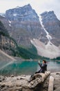 Tourist stting on the tree capturing the beautyful landscape in Moraine Lake, CANADA