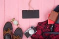 Tourist stuff -bag, passport, camera, compass, shoes, shirt, note pad and blank blackboard on pink wooden background Royalty Free Stock Photo