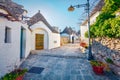 Tourist take picture of strret with trullo trulli - traditional Apulian dry stone hut with a conical roof. Splendid spring city