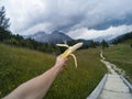 Tourist take a rest and eating babanas with a view on landscape of Dolomites moutains and a gree forest on a background