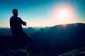 Tourist take a rest. Handsome young man sitting on the rock and enjoying view into misty rocky mountains. Royalty Free Stock Photo