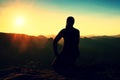 Tourist take a rest. Handsome young man sitting on the rock and enjoying view into misty rocky mountains. Royalty Free Stock Photo