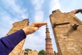 Tourist takes a forced perspective photo of her hand touching the Qutub Minar column in New Delhi India Royalty Free Stock Photo