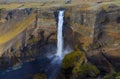 Tourist takes photo on mobile phone of second highest waterfall in Iceland - Haifoss. Picturesque sunrise view of deep canyon.