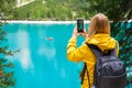 Tourist takes photo of stunning lake Braies in the Dolomite mountains with turquoise water