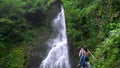 A tourist takes pictures of a waterfall.