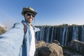 A tourist takes a selfie at Victoria Falls on the Zambezi River, located on the border between Zambia and Zimbabwe, the largest Royalty Free Stock Photo