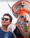 Tourist taking photo with colorful mask performer in Phi Ta Kon