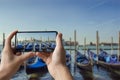 Tourist taking photo of gondolas pier row anchored on Canal Grande with San Giorgio Maggiore church in the background, Venice, Royalty Free Stock Photo