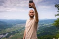 A tourist taking photo of himself while standing on top of the mountain