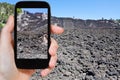 Tourist taking photo of lava flow on slope of Etna