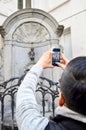 Tourist taking photo of Manneken Pis or Little Man Pee located near Grand Place in the city of Brussels, Belgium Royalty Free Stock Photo