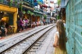 Tourist taking photo of narrow train railroad in old town in Hanoi