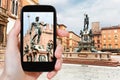 Tourist taking photo of Piazza Nettuno in Bologna