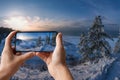 Tourist taking photo of snowy beach with dunes and Baltic sea coast surrounded by pine nd fir trees forest in Baltics