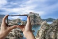 Tourist taking photo of stunning view of Dubrovnik city wall. Man holding phone and taking picture of fortress walls, rocky coast Royalty Free Stock Photo