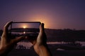 Tourist taking photo of sunset on the lake in spring. Boats silhouettes and the rays of the sun Royalty Free Stock Photo