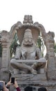 tourist taking photos of hypnotising stone carved statute of the Hindu god Vishnu in his Narsimha avatar, that is half lion