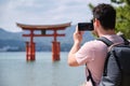 Tourist taking photos of Itsukushima Jinja Otorii on the sea of Miyajima, Japan. Royalty Free Stock Photo