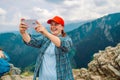 Tourist taking picture on her smartphone from top of mountain. Caucasian woman in hat and with backpack on rock. Travel Royalty Free Stock Photo