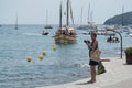 Tourist taking pictures of sailboats near the coast