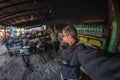 Tourist taking selfie at street food stall in India bus station while traveling. Fish eye view with indian sweets in foreground. Royalty Free Stock Photo