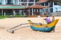 Tourist talking with local man sitting on traditional Sri Lankan fishing boat