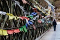 Tourist with tear colorful Tibetan prayer flags waving and swaddled with bridge over frozen river at Thangu and Chopta valley. Royalty Free Stock Photo