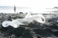 Tourist Teenager getting in the sea and ignoring the rubbish in a dirty beach with wasted plastic bottle and bag. Sunset at the