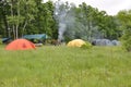 Tourist tent camp on a green clearing on the edge of the forest. Royalty Free Stock Photo