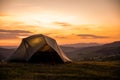 Tourist tent in the mountains under dramatic evening sky. Colorfull sunset in mountains. Camping travell concept. Traveler people