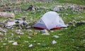 Tourist tent stands on green grass among stones