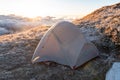 Tourist tent on top of the mountain. A pitched tent under blue morning sky. Sunlight over tourist tent, cold winter Royalty Free Stock Photo