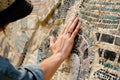 tourist touching the texture of an ancient replica mosaic wall