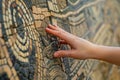 tourist touching the texture of an ancient replica mosaic wall