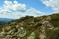 A tourist trail climbs over stones to the top of a hill overgrown with grass in a picturesque mountain valley on a cloudy summer Royalty Free Stock Photo