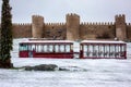 Tourist tram circulating in front of the wall of the Spanish city of Avila on a beautiful snowy day