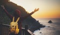 Tourist traveler with backpack standing with raised hands, hiker looking on sunset to valley in trip, hipster young girl enjoying Royalty Free Stock Photo