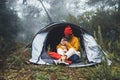 Tourist traveler in camp tent hugging red shiba inu on background froggy rain forest, hiker woman kiss puppy dog in mist nature Royalty Free Stock Photo