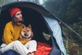 Tourist traveler in camp tent hugging red shiba inu on background froggy rain forest, hiker woman with puppy dog in mist nature Royalty Free Stock Photo
