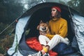 Tourist traveler in camp tent hugging red shiba inu on background froggy rain forest, hiker woman with puppy dog in mist nature Royalty Free Stock Photo