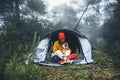 Tourist traveler in camp tent hugging red shiba inu on background froggy rain forest, smile woman with puppy dog in mist nature Royalty Free Stock Photo
