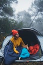 Tourist traveler hugging relaxation red shiba inu in camp tent on background blue froggy forest, hiker woman with puppy dog Royalty Free Stock Photo