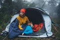 Tourist traveler hugging relaxation red shiba inu in camp tent on background froggy forest, hiker woman with puppy dog in mist Royalty Free Stock Photo