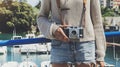 Tourist traveler photographer making pictures sea scape on vintage photo camera on background yacht and boat piar, hipster girl en Royalty Free Stock Photo