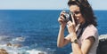 Tourist traveler photographer making pictures sea scape on vintage photo camera on background yacht and boat piar, hipster girl Royalty Free Stock Photo