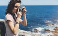 Tourist traveler photographer making pictures sea scape on vintage photo camera on background yacht and boat piar, hipster girl Royalty Free Stock Photo