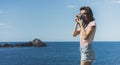 Tourist traveler photographer making pictures sea scape on vintage photo camera on background yacht and boat piar, hipster girl Royalty Free Stock Photo